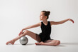 © Kiryakova Anna - A girl in a gymnastic black bodysuit performs exercises with a ball. White background
