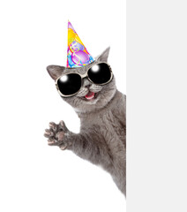 Aufkleber - Happy cat wearing party's cap look from behind empty white banner and waved his paw. isolated on white background
