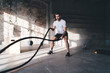 © BullRun - Strong man doing exercises with battle ropes in gym