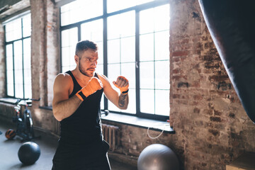 Wall Mural - Determined sportsman standing and waiting for punch bag in gym