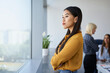© baranq - Thoughtful young Asian woman looking through window in office