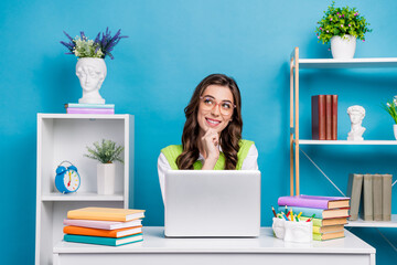 Wall Mural - Photo of pretty young girl eyeglasses workstation look empty space dressed stylish green outfit isolated on blue color background workspace