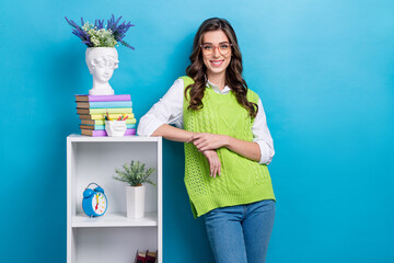 Wall Mural - Photo portrait of lovely young lady specs lean on shelf classroom interior dressed stylish green clothes isolated on blue color background