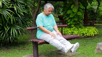 Wall Mural - Asian elderly woman exercising in the park She did stretching exercises to relieve knee pain. The concept of healthy health care in retirement. bone disease in the elderly