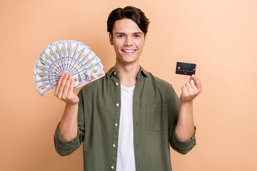 Sticker - Photo of pleasant good mood cool guy with brunet hair dressed khaki shirt holding money debit card isolated on beige color background