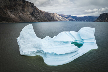 Big blue iceberg reflecting in water floats in the sea by Broughton Island, Nunavut, Canada. auyuittuq national park