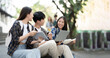© Parichat - Young Asian college students reading books, studying on laptop, preparing for exam or working on group project while sitting on staircase of college campus.
