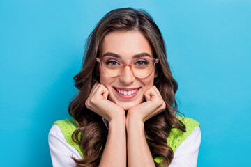 Poster - Portrait of adorable cheerful girl arms touch cheeks beaming smile isolated on blue color background