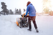 © Sabrewolf - A man with a yellow snow-covered snowblower clears the area from snow. Clearing the access road to the house from snowfall.
