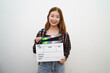 © Daniel Pawer - Portrait of young Asian student holding clapperboard smiling with backpack isolated red background. Film major student concept.