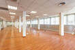 © Pavel - Large empty space with ceiling tiles, fluorescent lights, light brown laminate flooring and white painted columns. Large office space for rent just renovated and unfurnished.