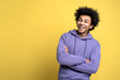 © Maria Vitkovska - Portrait of smiling African American man with arms crossed isolated on yellow background, copy space. Happy fashion model wearing stylish casual clothes posing for photo looking away, studio shot