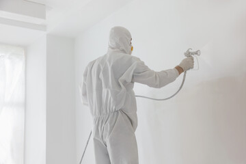 Wall Mural - Decorator painting white wall with spray indoors, back view