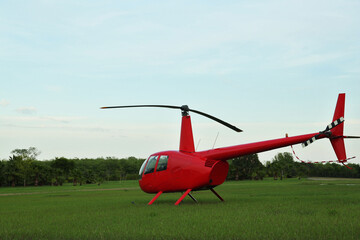 Wall Mural - Modern red helicopter on green grass outdoors