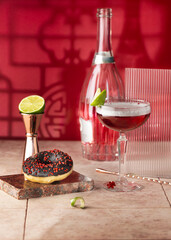 Wall Mural - Beautiful red cocktail with champagne and liquer,garnished with slice of lime onred background.Close up of drink in crystal glass.