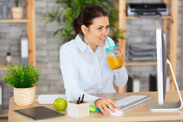 happy healthy woman drinking orange juice at work