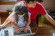 © Cavan Images - Above-view of girl sitting on father's lap in front of computer