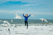 Child chasing birds near summer beach. Excited boy running on the beach with flying seagulls birds.