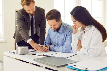 Wall Mural - Young couple buying house and signing contract at real estate agent's office. Happy man and woman sitting at office table and putting signatures on contract agreement. Mortgage, buying house concept