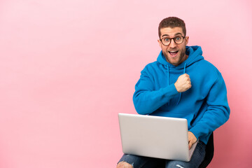 Poster - Young man sitting on a chair with laptop celebrating a victory