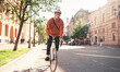 © muse studio - A young male hipster cyclist riding to work on a bicycle wearing a helmet. Eco transport for the city.