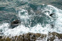 View From A Height Of Turquoise Water. The Waves Wash Over The Rocks Near The Shore.