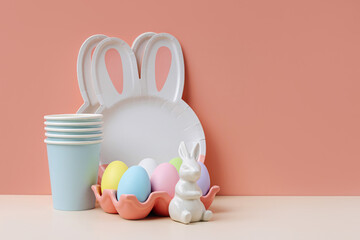 Cute paper plates in the shape of a bunny with  Easter eggs, candy and decorations. Happy Easter. Set of holiday disposable tableware for party or picnic.