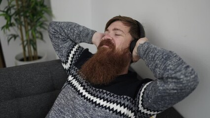 Sticker - Young redhead man listening to music relaxed on sofa at home