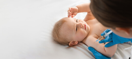 doctor vaccinating smiling baby in clinic. one year little baby get an injection. pediatrician and p