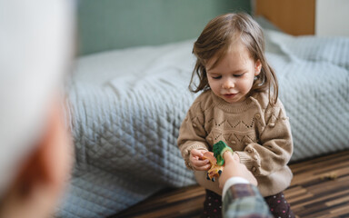 Wall Mural - small caucasian girl toddler child play with finger puppets at home