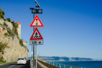 Car road signs: traffic lights, pedestrians beware. Signs on a blue sky background, next to the sea