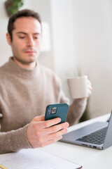 Crop man using laptop and smartphone