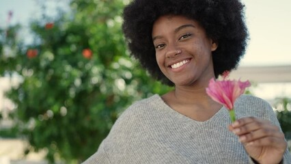 Sticker - African american woman smiling confident holding flower at park