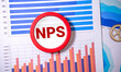 NPS text on notebook on graph background with pen and magnifier.