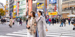 Asian woman friends crossing street crosswalk with crowd of people during shopping at Shibuya, Tokyo, Japan in autumn. Attractive girl enjoy and fun outdoor lifestyle travel city on holiday vacation.