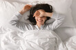© Prostock-studio - Glad smiling young european woman sleeping on white bed, waking up, enjoying vacation, good morning