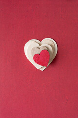 Wall Mural - isolated pile of variously sized wood heart ornaments on a deep valentine red paper background