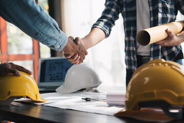 Close up view of engineering team shaking hands after the deal is completed. Team planning for architecture project. .