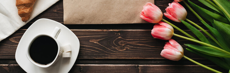 Wall Mural - Cup of coffee with a bouquet of pink Tulip flowers and a croissant for the morning Breakfast. Flat lay, top view with copy space. Spring greeting card template