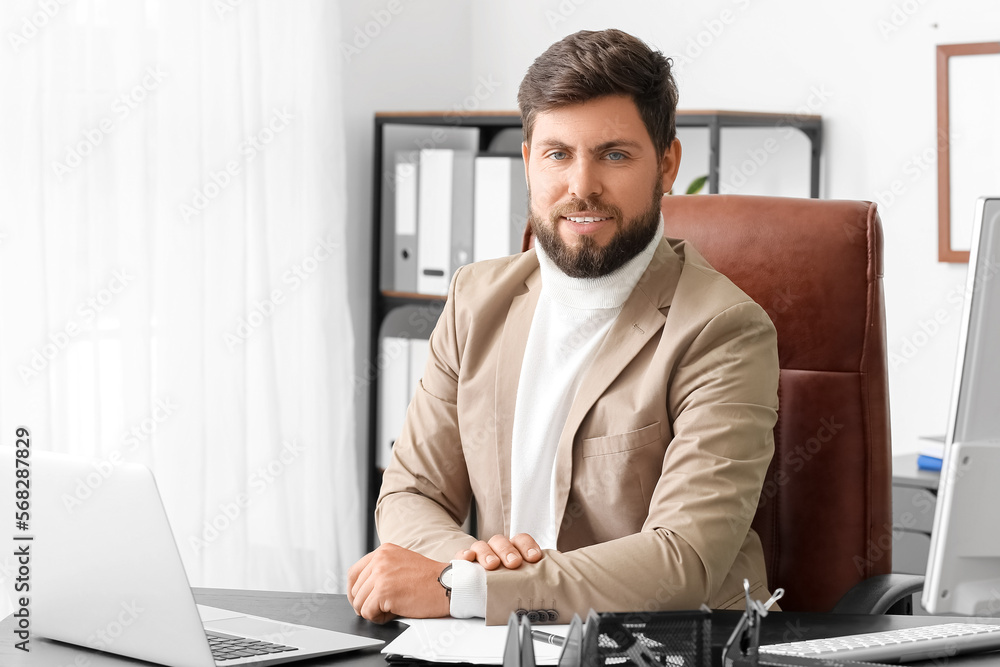 Handsome businessman sitting at table in office
