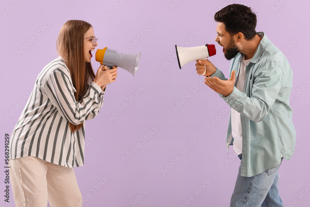 Young couple shouting into megaphones on lilac background
