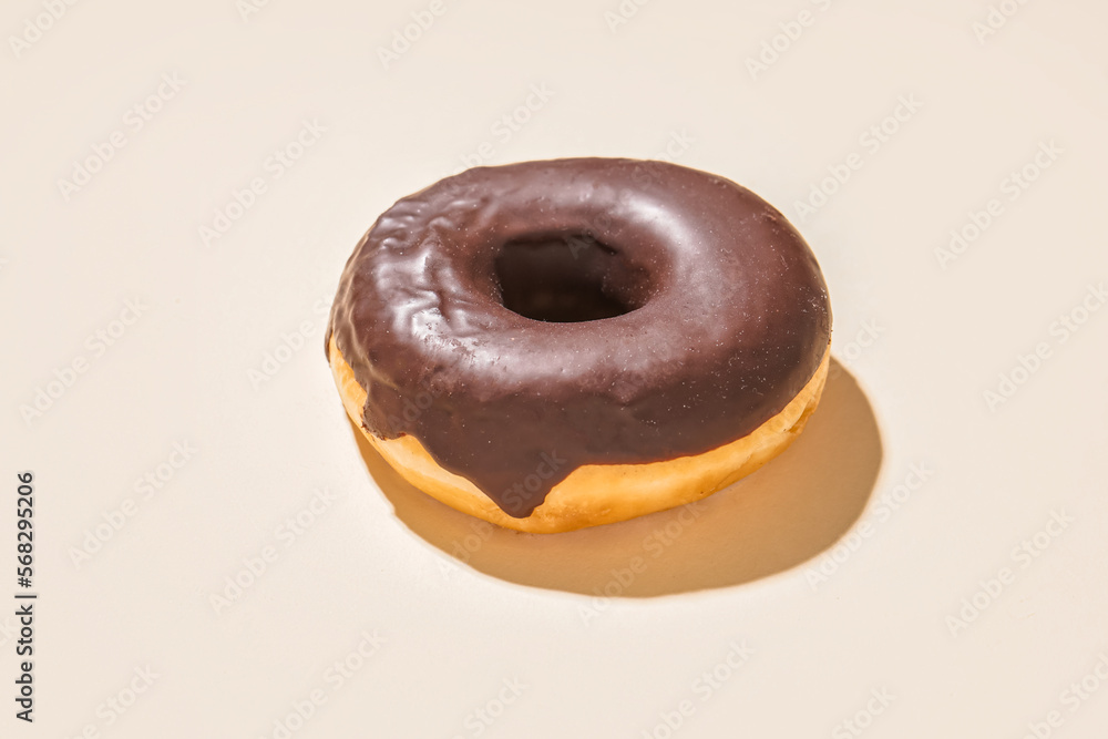 Delicious chocolate donut on beige background