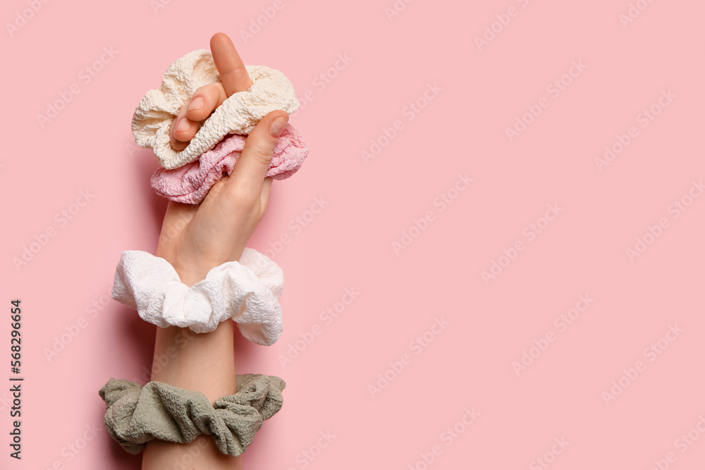Female hand with different scrunchies on pink background