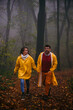 © La Famiglia - A young woman with her boyfriend in a forest, both looking around and smiling. Happy young couple walking together on a rainy day in the forest.