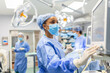 © Graphicroyalty - Anesthetist Working In Operating Theatre Wearing Protecive Gear checking monitors while sedating patient before surgical procedure in hospital