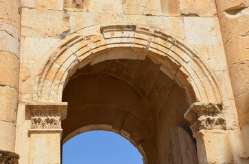 Sunny temples, arches, the Nymphaeum, stone ornaments, columns and column bases on the ruins of the city of Jerash in Jordan.