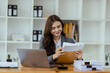 © SOMKID - Businesswoman working with laptop and document paper sitting at desk in office workplace, business finance and accounting, business online training concept.