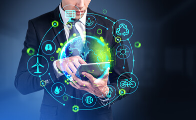 businessman using tablet, earth globe hologram with green energy hud