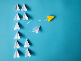Wall Mural - Yellow and white paper airplanes origami leaving other white airplanes on blue background with customizable space for text. Leadership skills concept