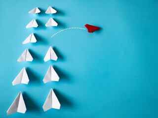Wall Mural - Red paper plane origami leaving other white planes on blue background with customizable space for text. Leadership skills concept